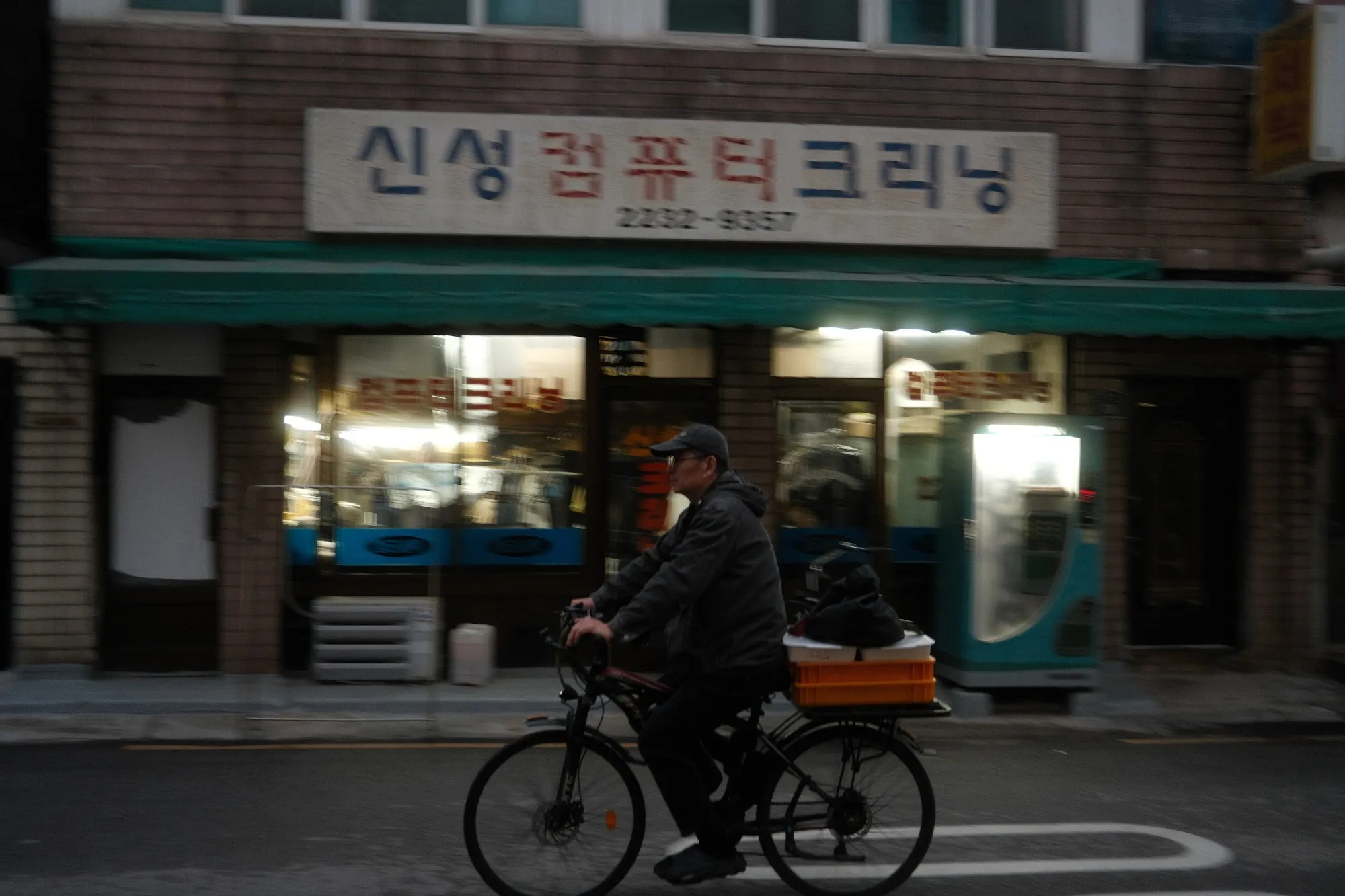 A cyclist passing a shopfront with Korean signage