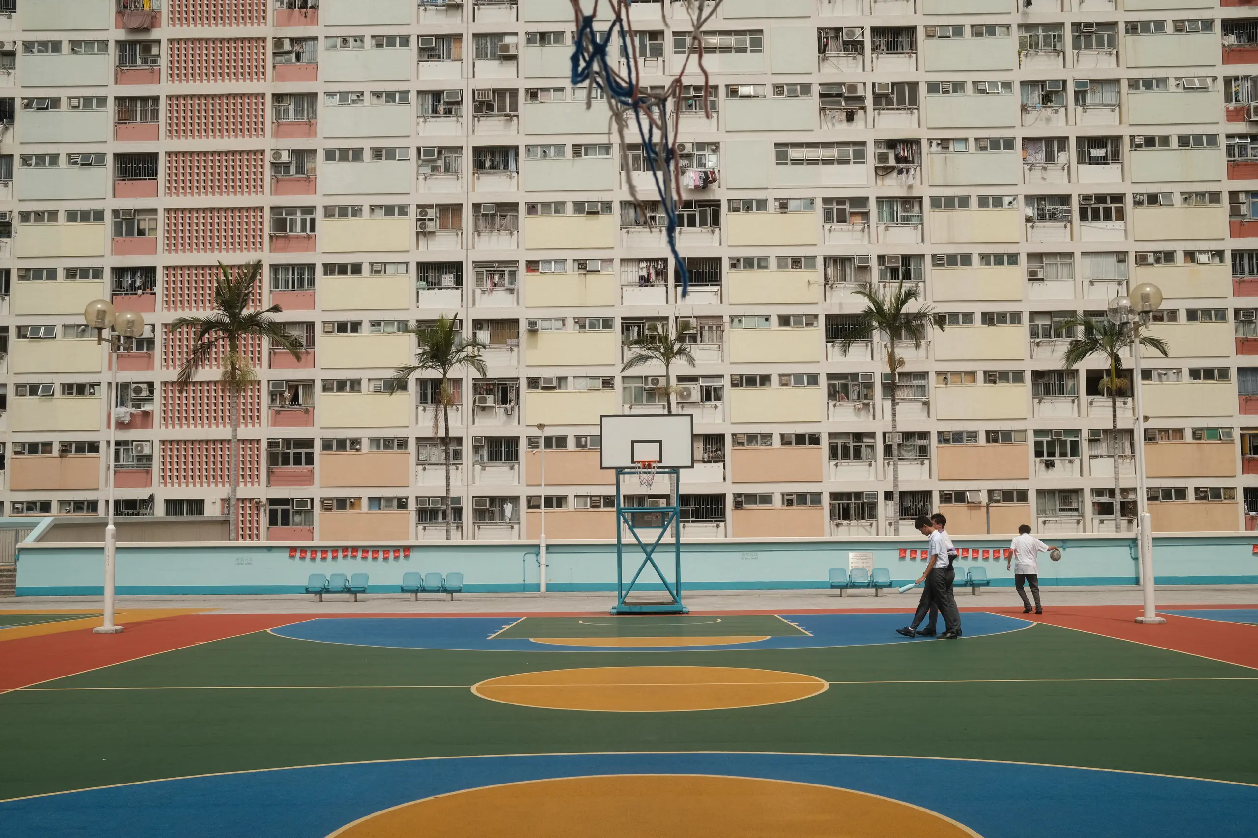 A basketball court in front of the pastel towers of Choi Hung Estate