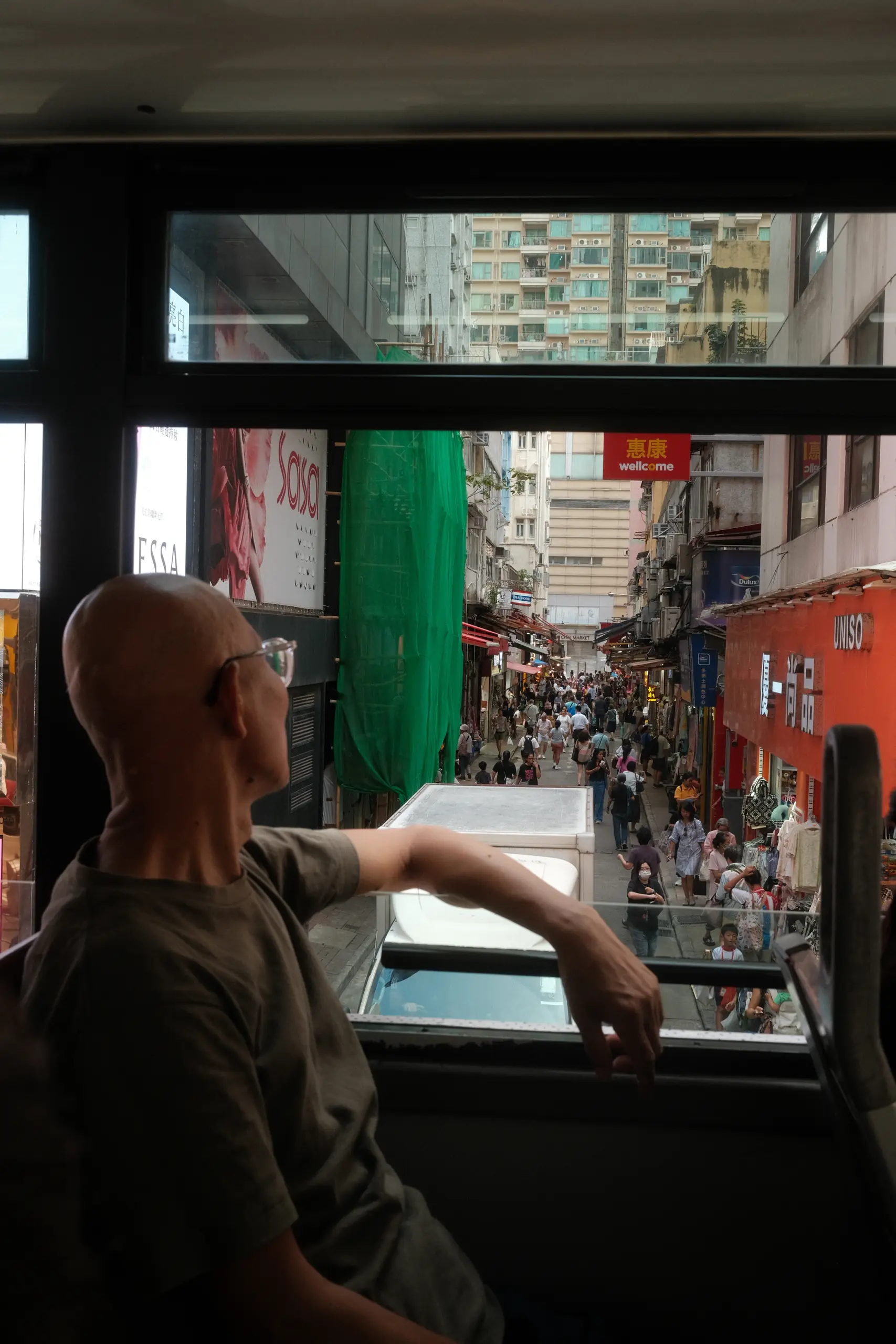 A man leaning out of the open window of a tram upper deck