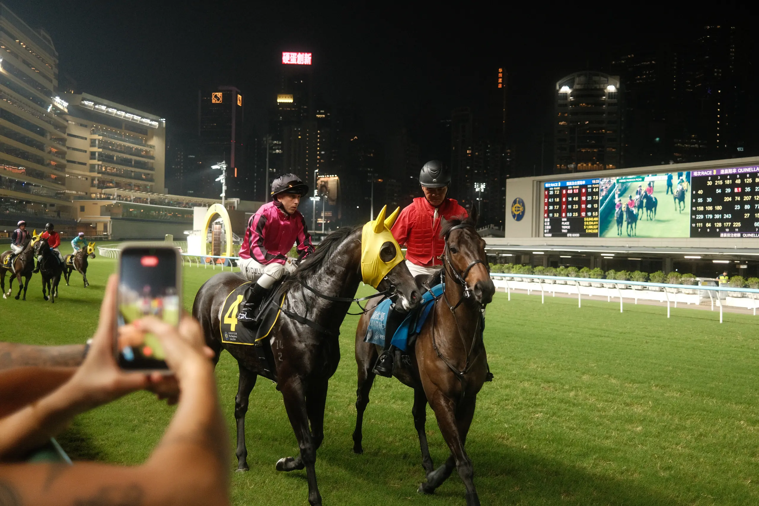 Jockeys walking their horses past the stands at Happy Valley