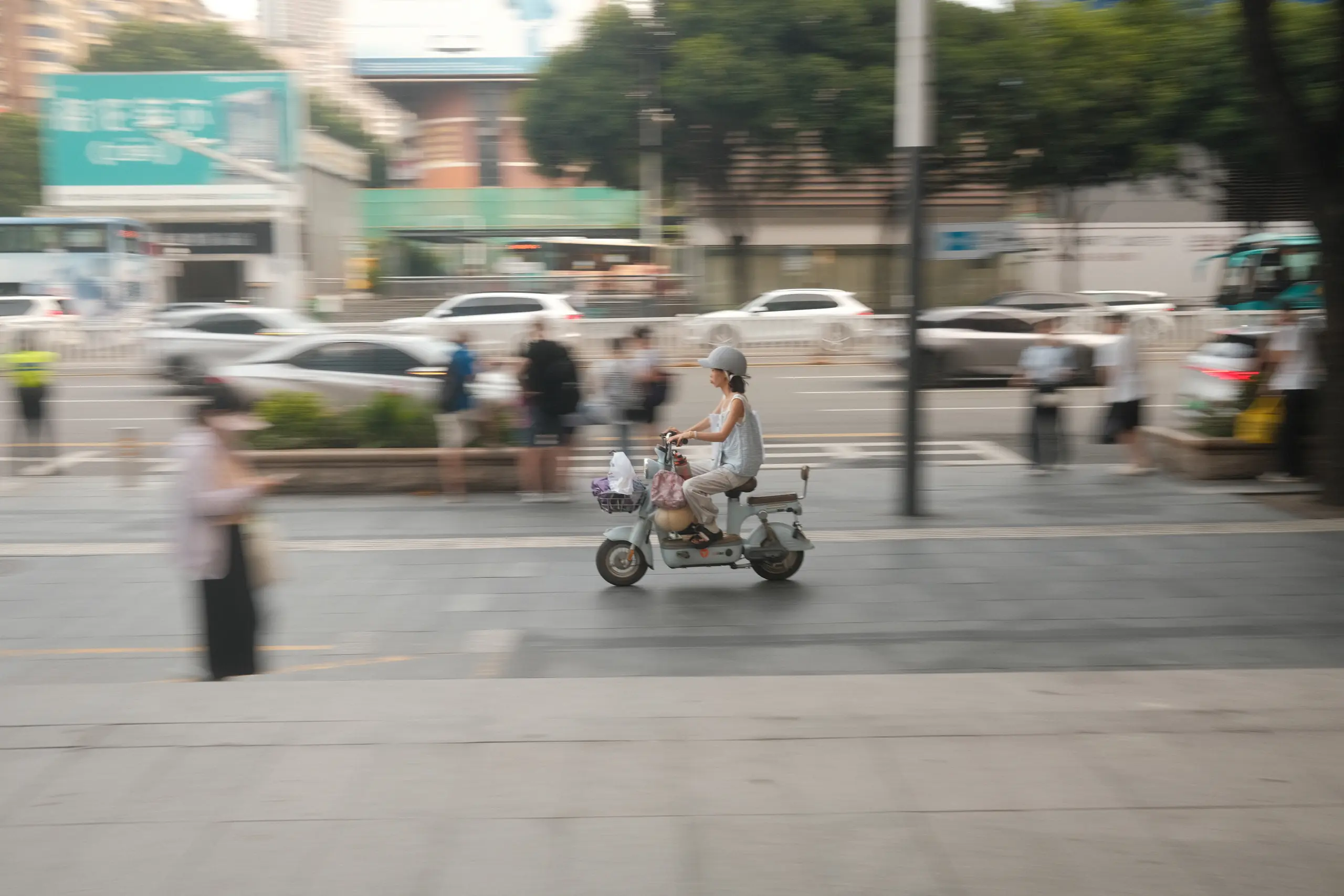 A woman on an electric scooter blurring past a bus
