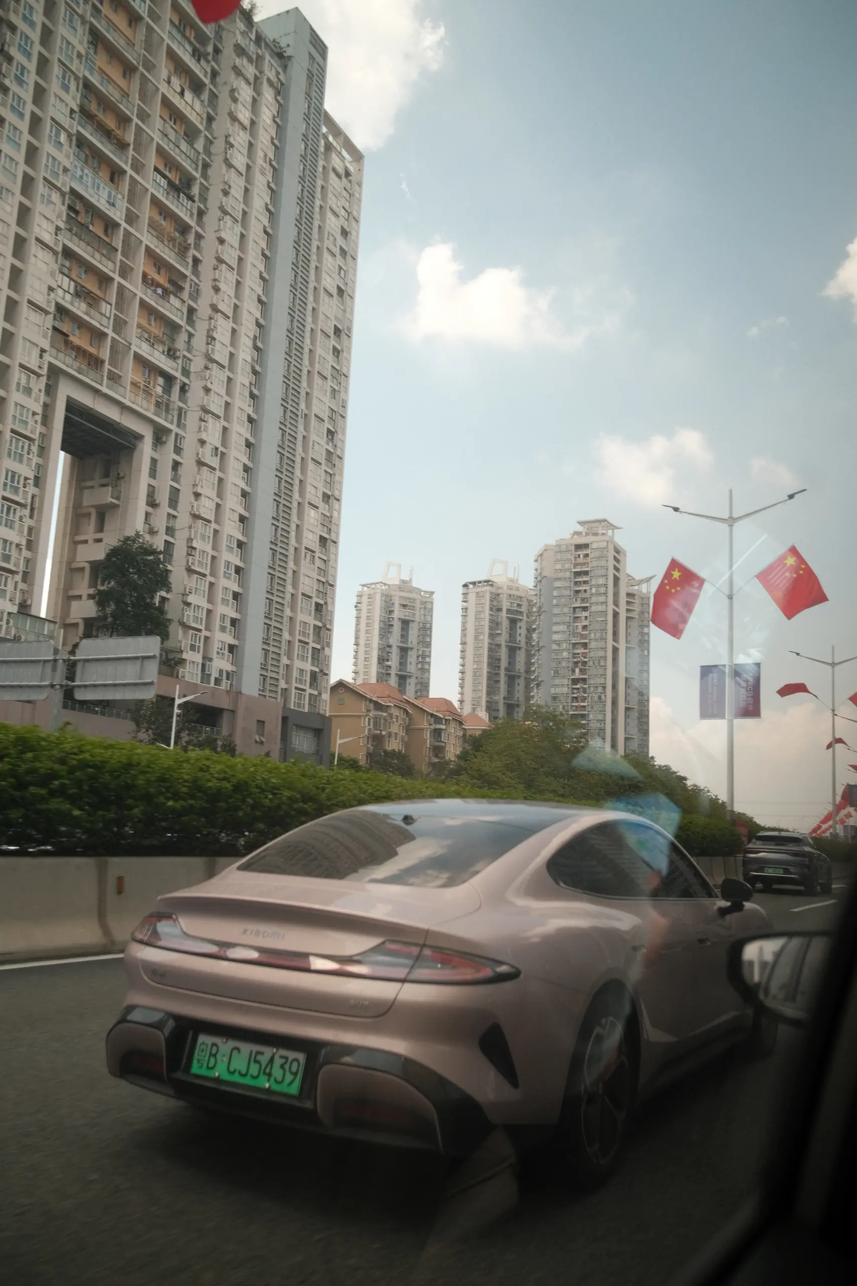 An electric car passing under red flags on a Shenzhen street