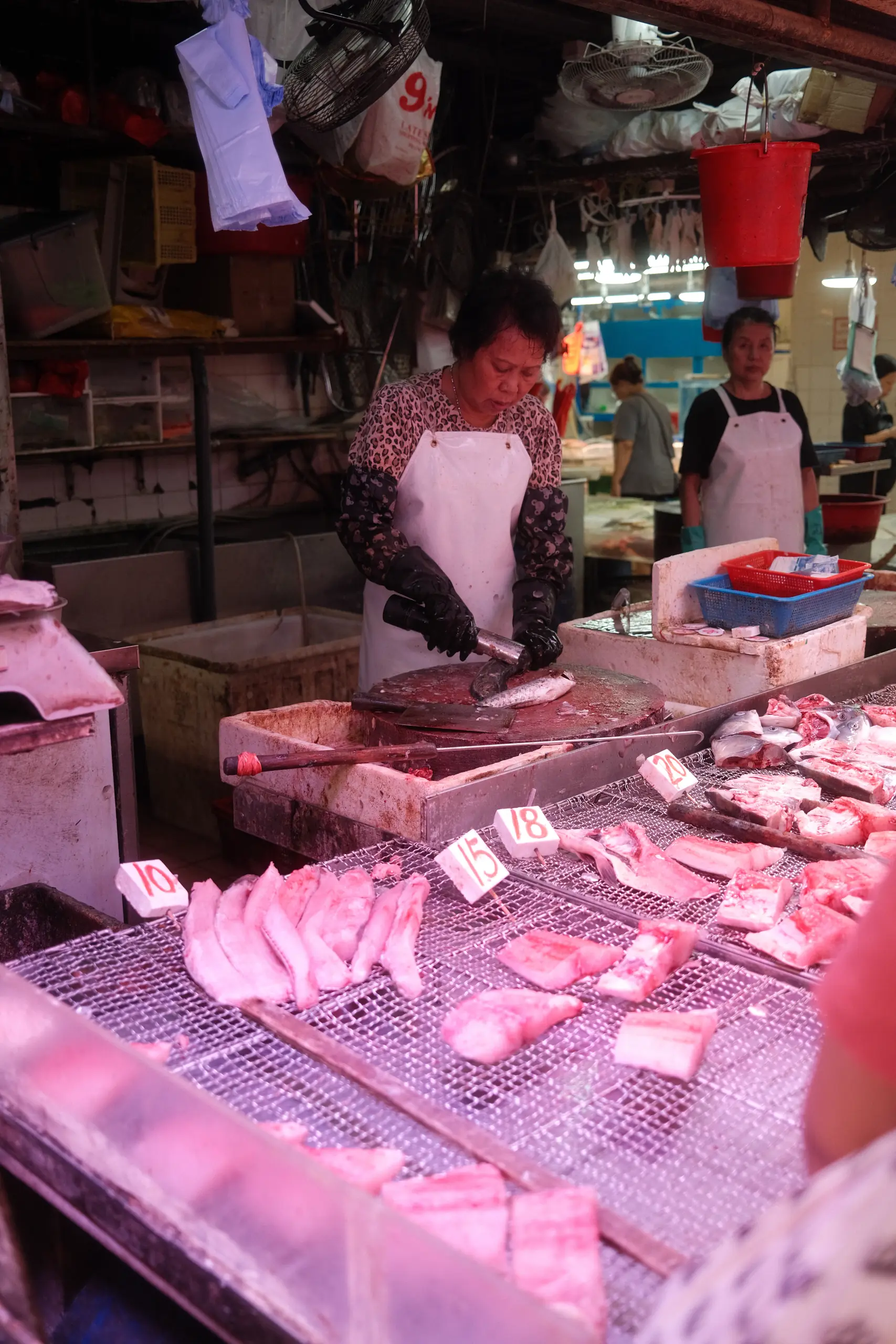 A butcher at a market stall under pink lights
