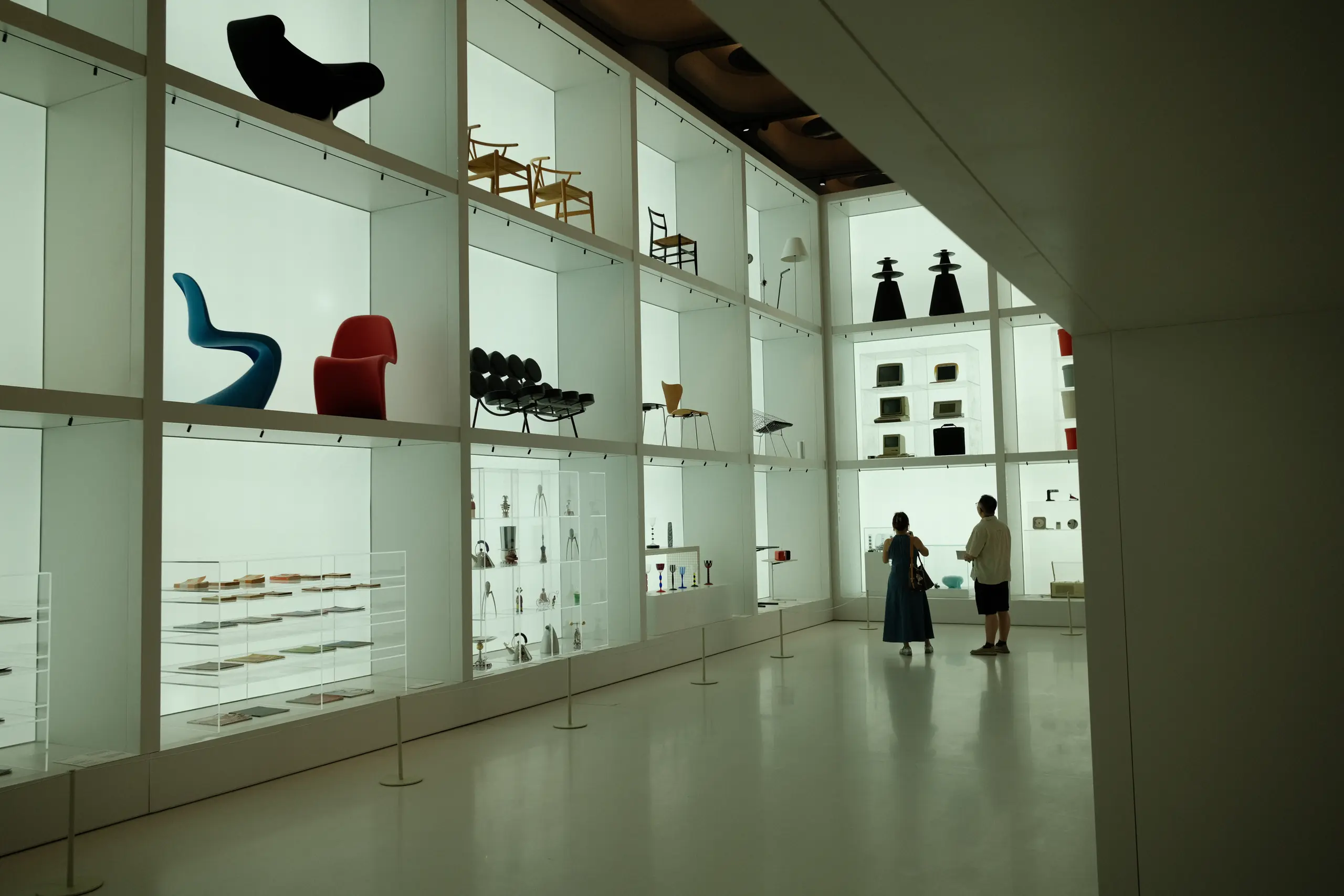 Design objects on lit shelves inside the museum