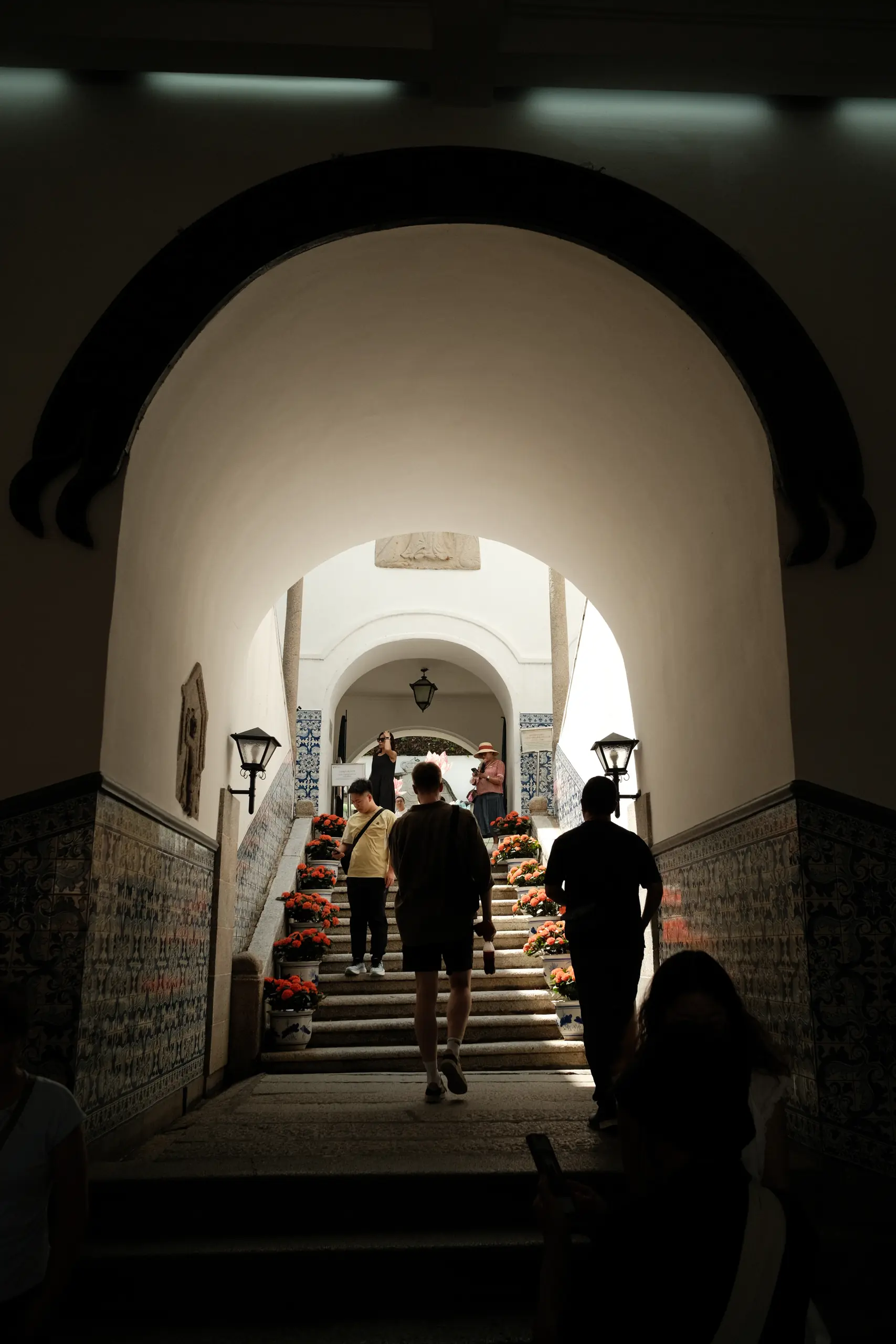 People climbing a tiled stairway under an arch