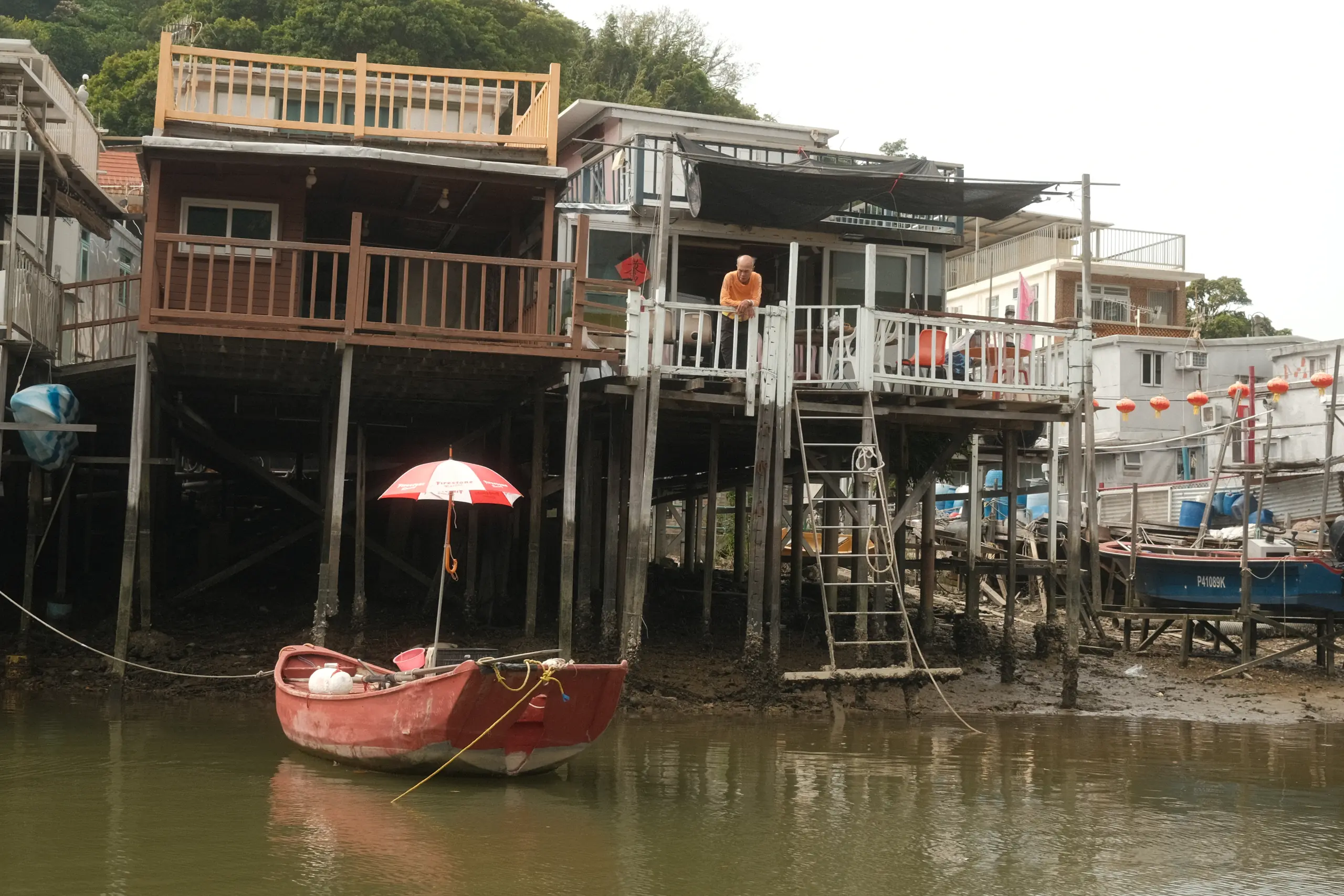 A red boat with a red umbrella moored below stilt houses