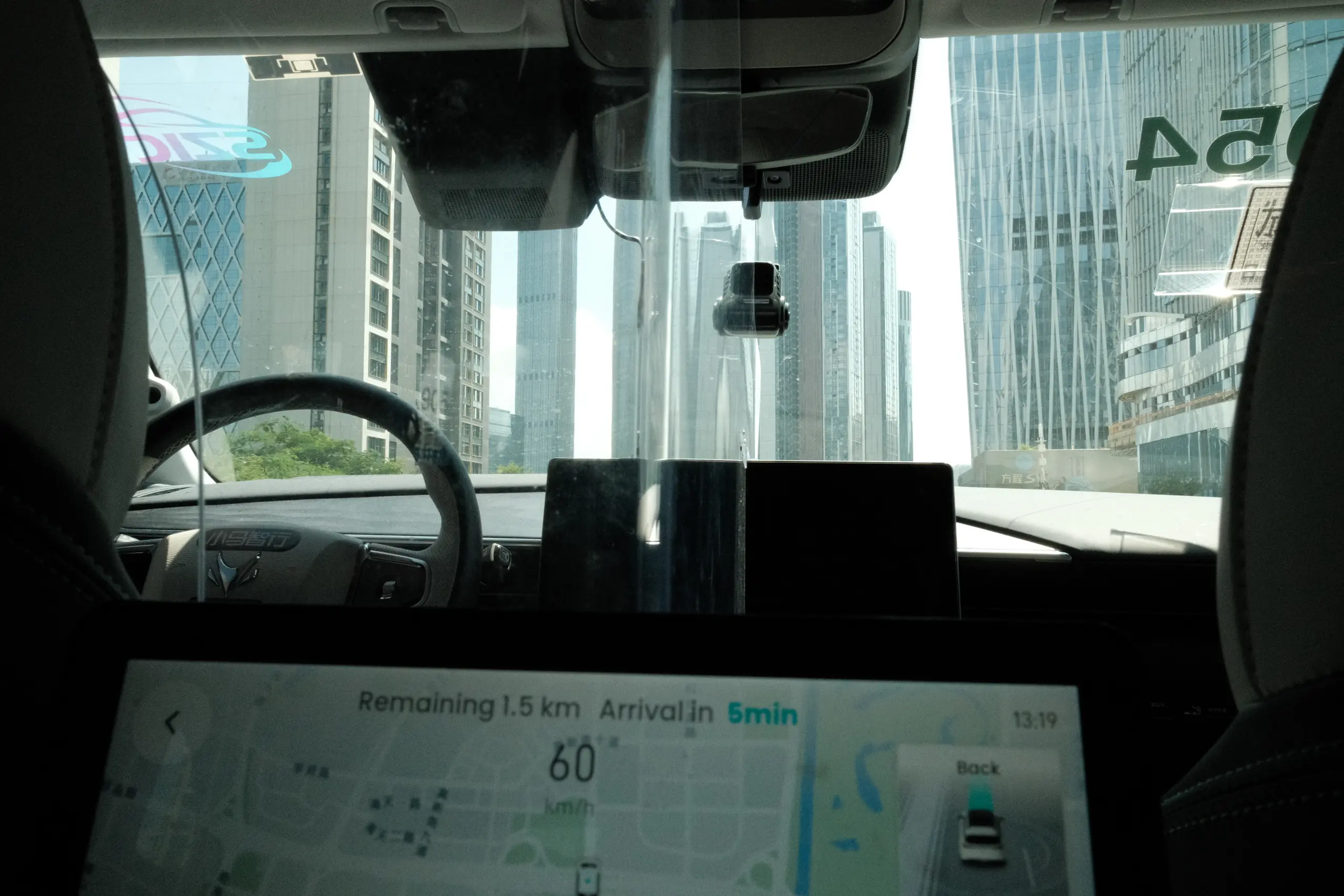 The empty driver seat of a Pony.ai robotaxi, the screen showing the route and remaining distance