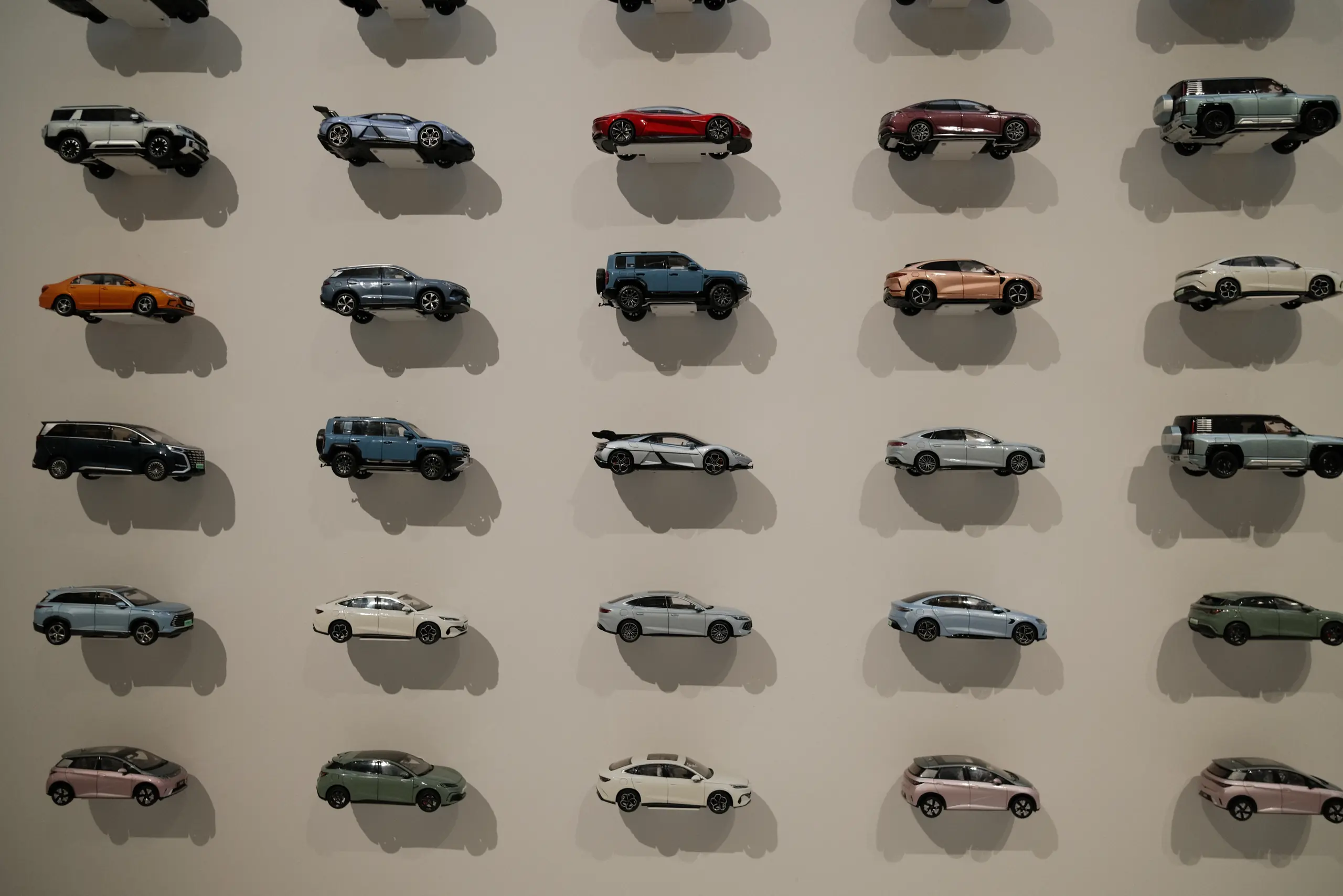 Rows of model cars mounted on a white wall