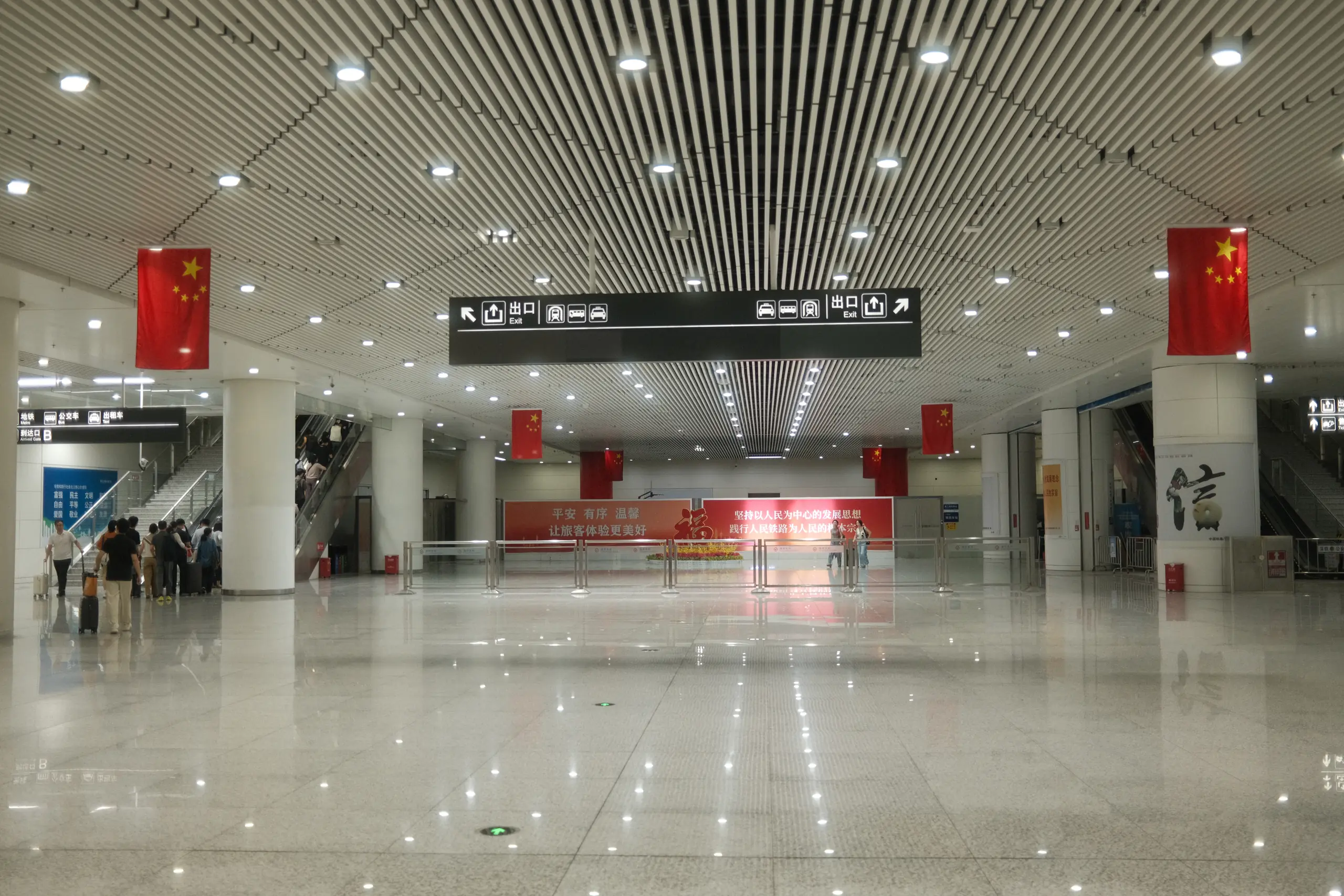 The arrivals hall at Futian station, empty marble under rows of red flags