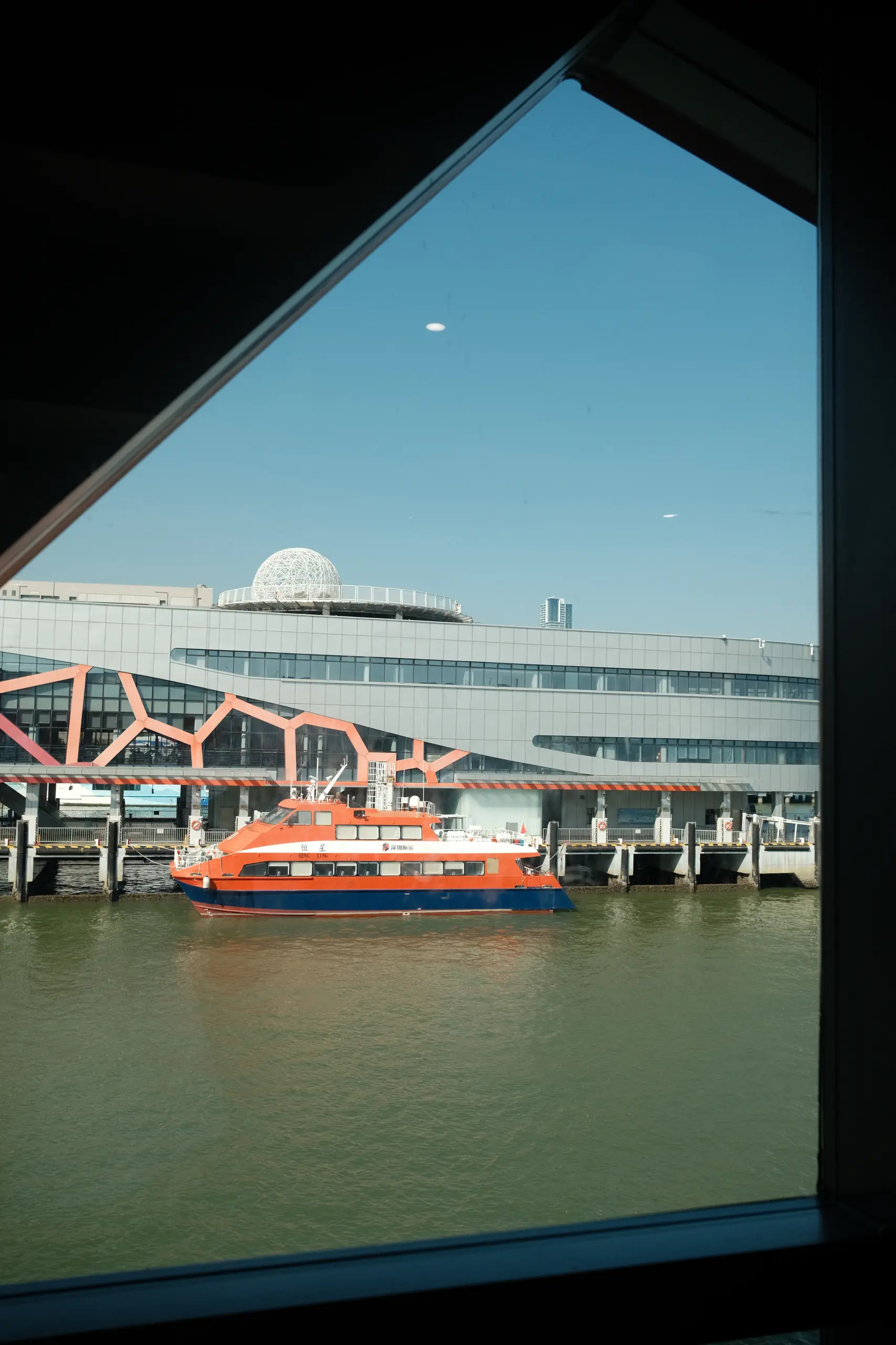 An orange ferry at the Shekou terminal seen through the waiting-room window