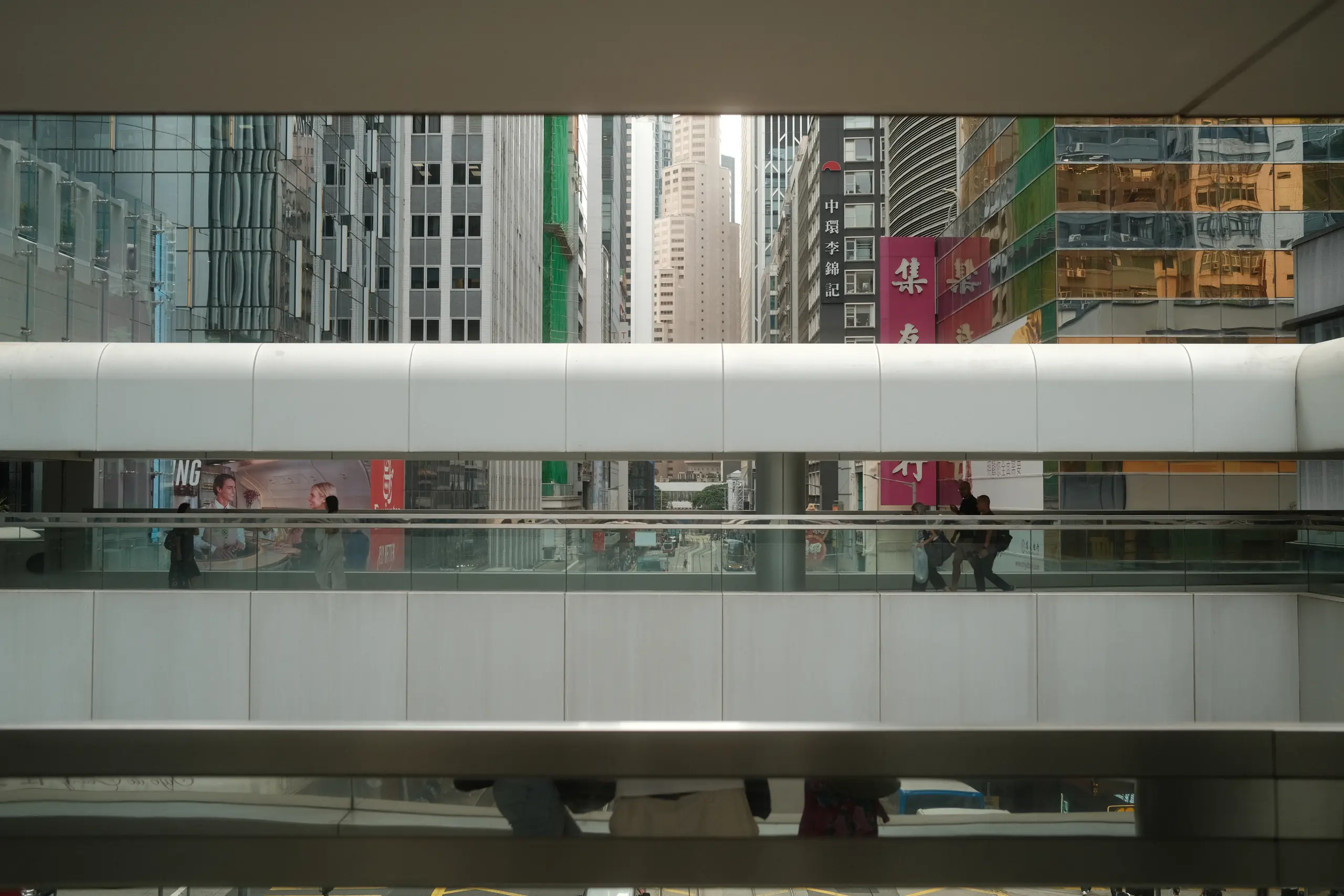 A glass footbridge in Central with people crossing between office towers
