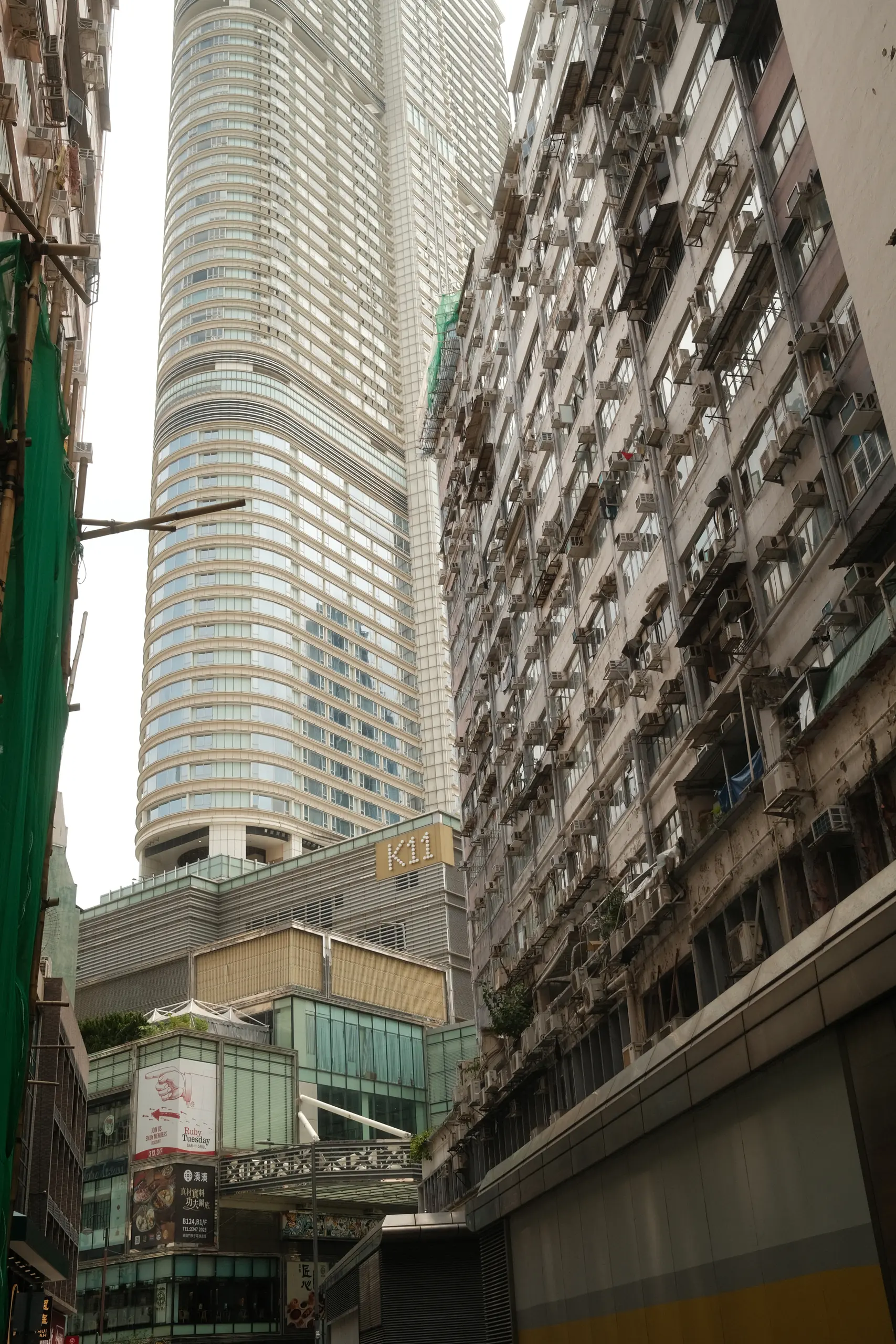 A glass tower rising behind an old apartment block