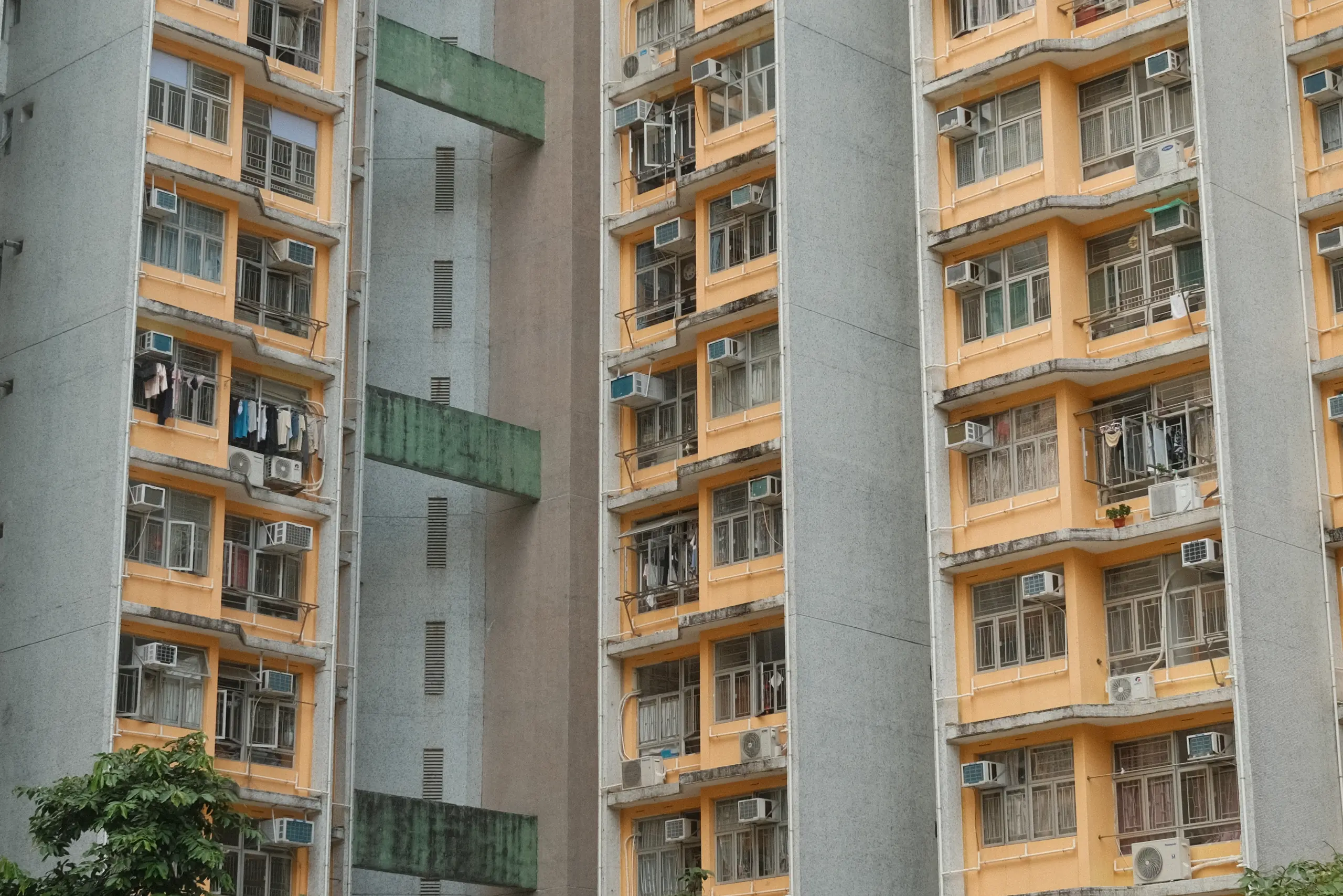 The yellow and green facade of a public housing estate in Kowloon
