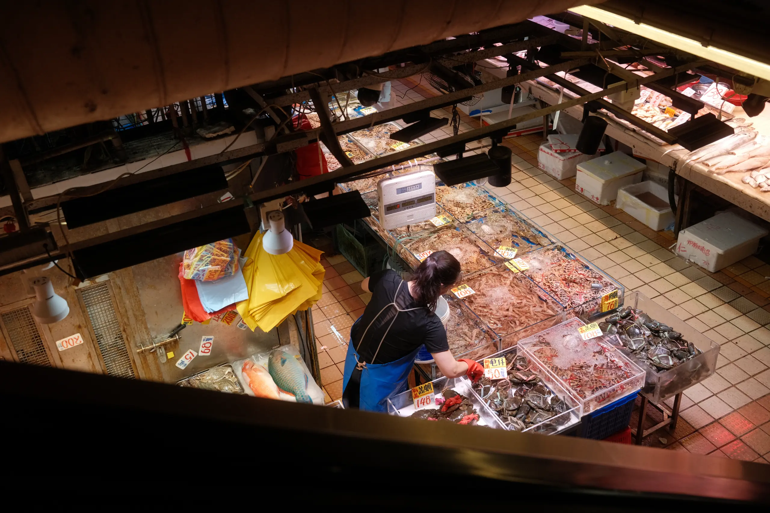 Vegetable and meat stalls in a wet market seen from the floor above